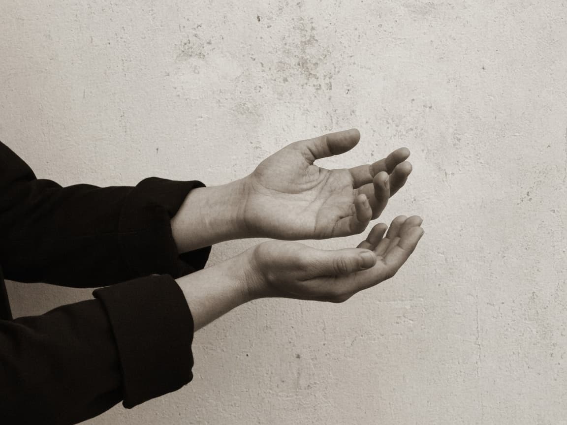 Hands at rest against plaster, skin texture left visible.